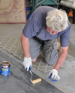 Rolling the glue on both folds of the tarp.
